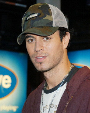 Enrique Iglesias performing live at a concert with a vibrant stage backdrop