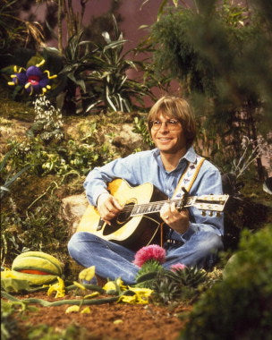 A collection of John Denver vinyl records displayed on a vintage turntable.