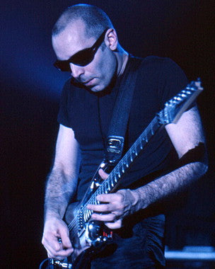 Close-up of a guitarist practicing Joe Satriani's techniques in a home studio.