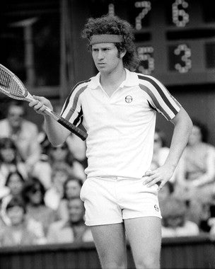 Close-up of a John McEnroe autographed tennis racket showcasing signature.