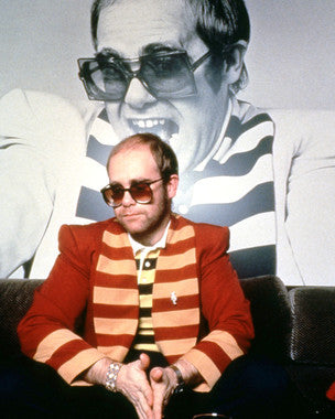 Elton John performing live on stage with bright lights